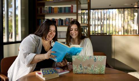 Two students reading one book together